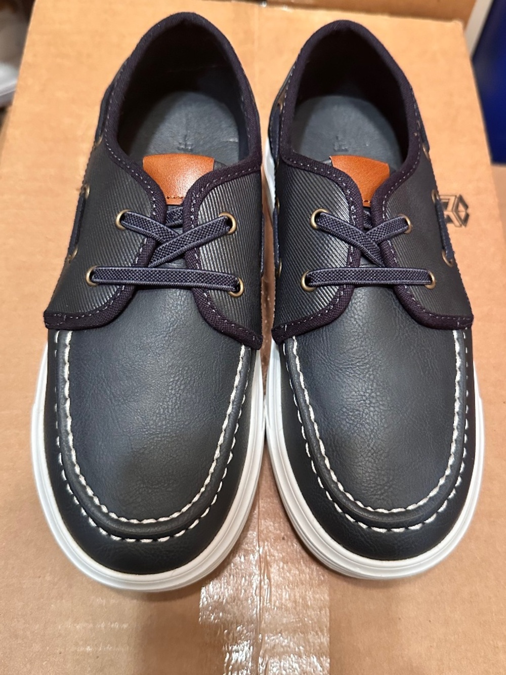 Bruno Marc boat shoes feature a dark blue upper with a brown tongue detail and w